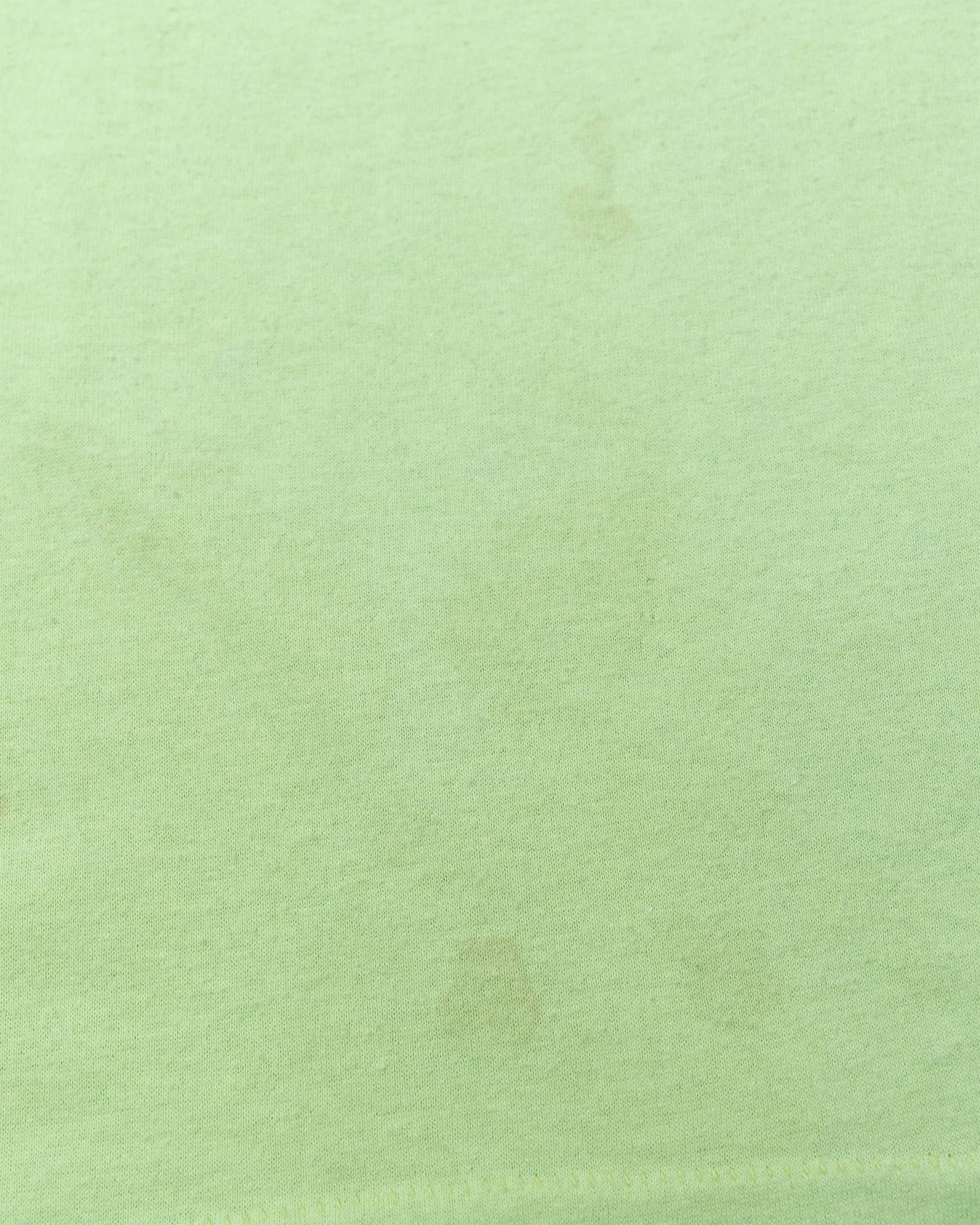 Close-up of a few small spots on front of vintage neon green Deja Vu Showgirls T-shirt.