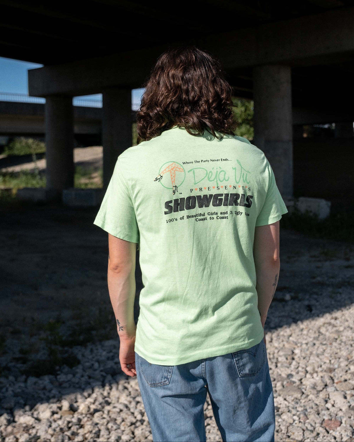 Back view of model wearing late-1980s Deja Vu Showgirls neon green T-shirt with large coast-to-coast graphic.