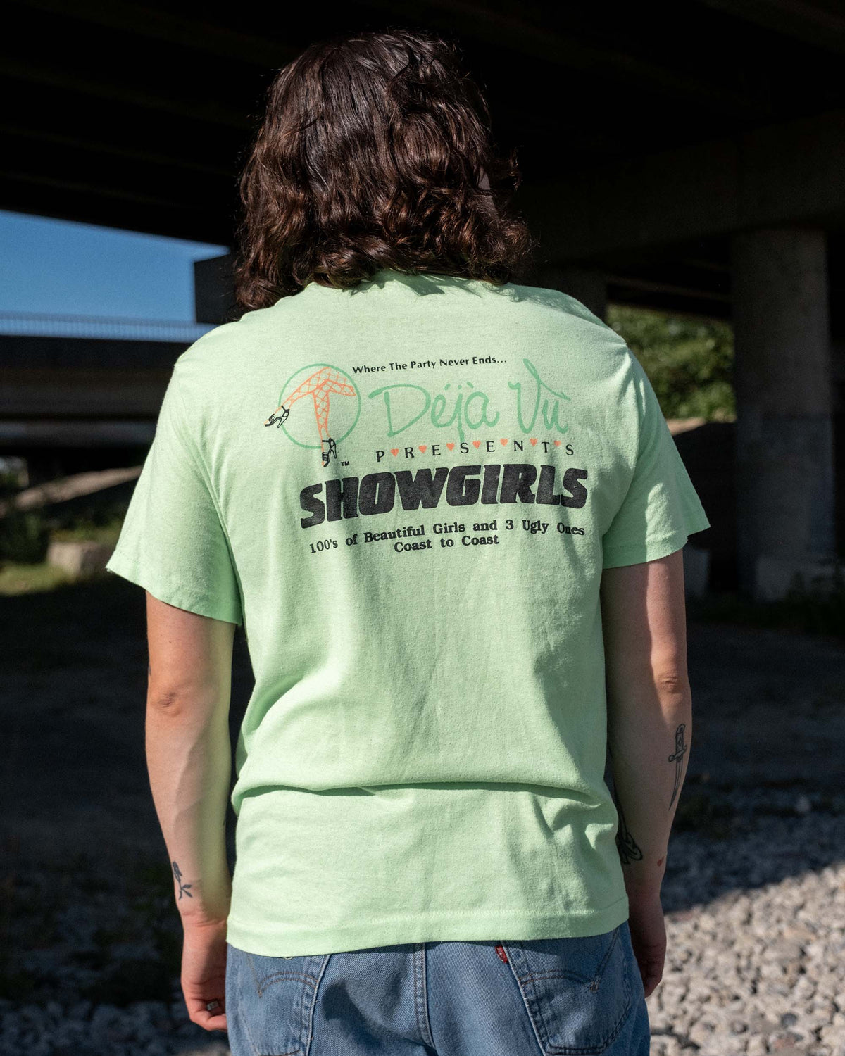 Back view of model wearing late-1980s Deja Vu Showgirls neon green T-shirt with large coast-to-coast graphics 