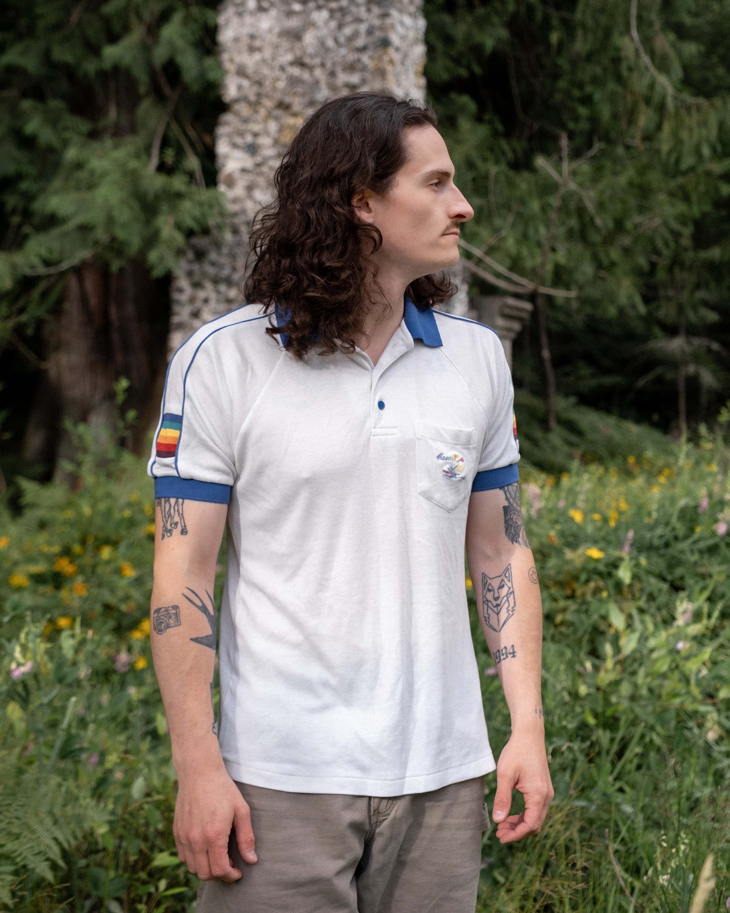 Model wearing vintage 1980s 5 Stars Hawaii polo with blue trim and rainbow sleeve stripes