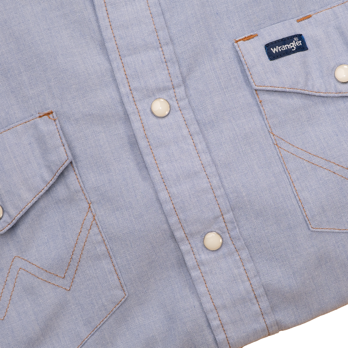 Pearl snap front and chest pocket details on faded blue Wrangler shirt